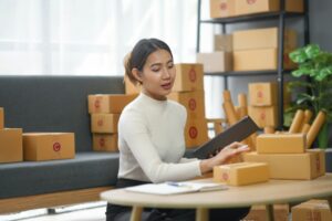 Young woman organizing cardboard boxes for e-commerce business at home office